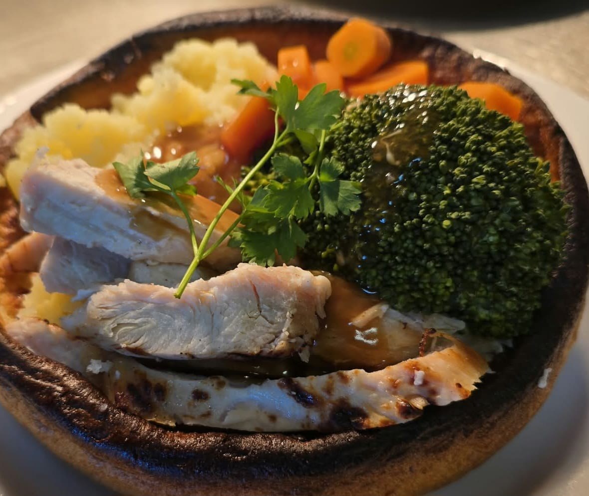 Roast chicken in a giant Yorkshire pudding with mash, carrots and broccoli