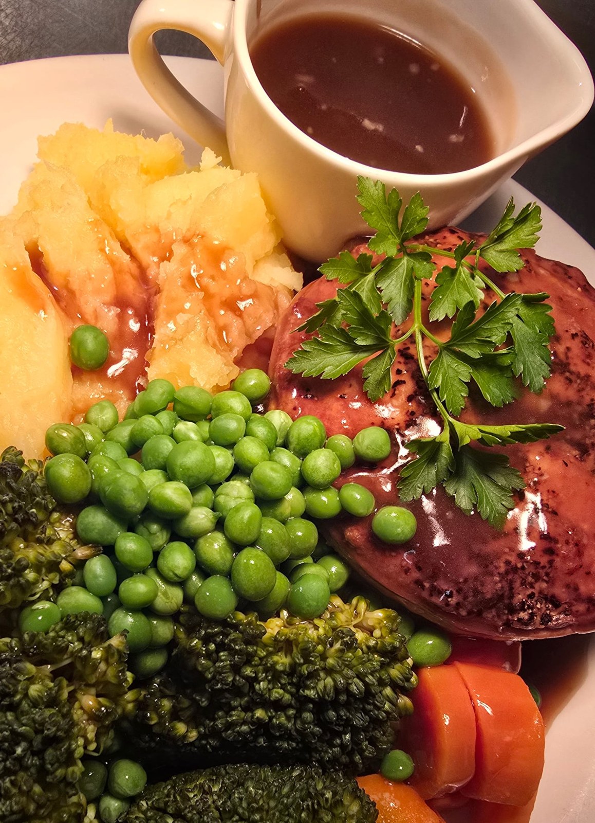 Home-made pie with mash, peas, vegetables and a jug of gravy